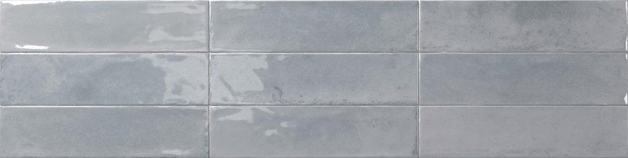 Eight glossy Relic 2.7 x 11 Porcelain Tiles in light gray are arranged in two horizontal rows, creating a modern wall or backsplash design with subtle shade variation for depth.