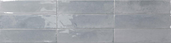 Eight glossy Relic 2.7 x 11 Porcelain Tiles in light gray are arranged in two horizontal rows, creating a modern wall or backsplash design with subtle shade variation for depth.