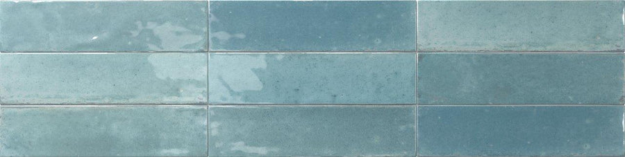 Relic 2.7 x 11 Porcelain Tiles are rectangular blue-green tiles with a glossy finish, arranged horizontally and featuring visible shade variation in both color and texture.