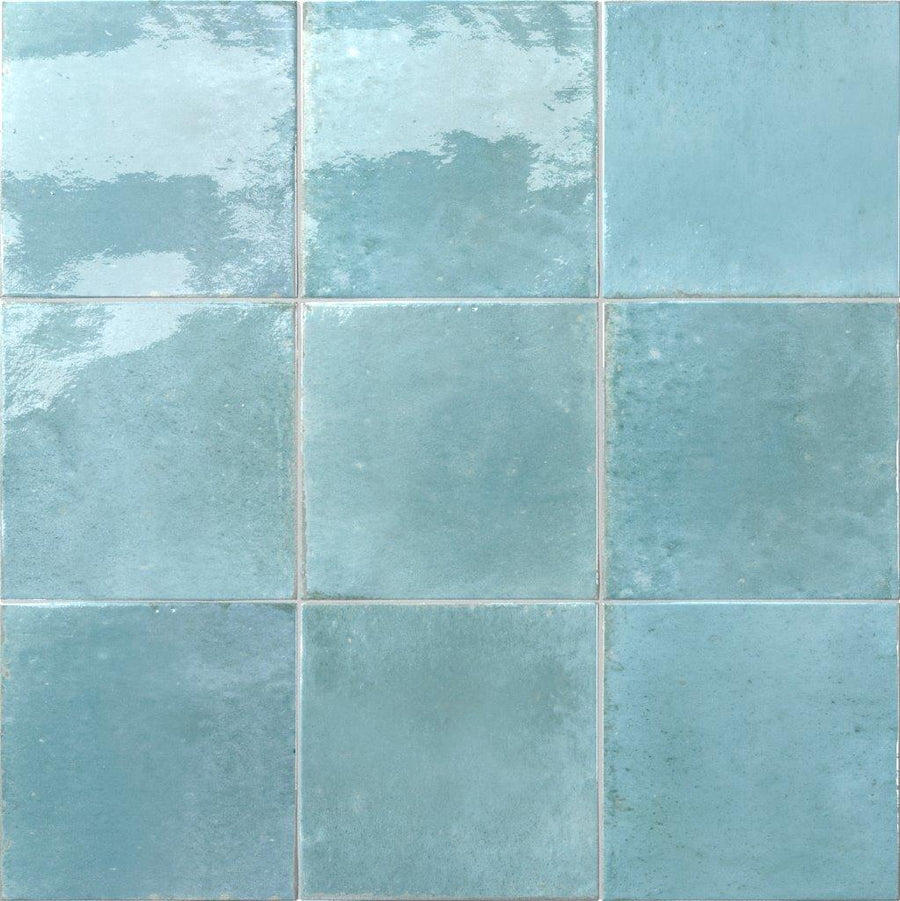 Nine glossy Relic 5.8 x 5.8 porcelain tiles, square and blue with subtle shade variation and textured, reflective surfaces, arranged in a three-by-three grid. Part of the Relic series with slightly uneven finish.