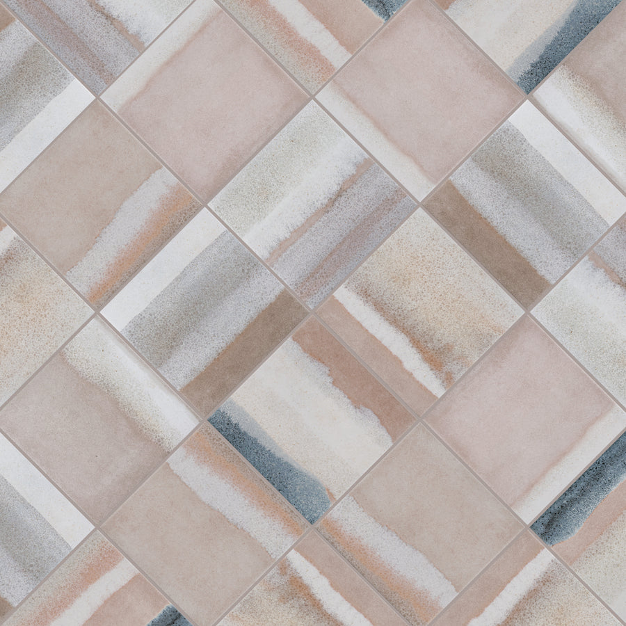 A close-up of square ceramic tiles arranged diagonally, featuring a mix of beige, taupe, gray, and white streaks with a matte finish, creating an abstract, watercolor-like pattern on each tile.