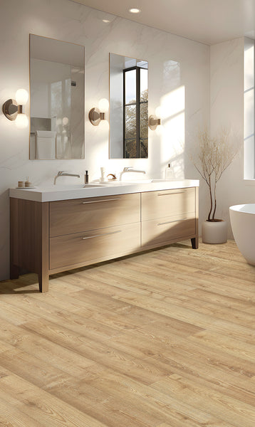 Modern bathroom with a double-sink wooden vanity, two mirrors, wall-mounted lights, a freestanding bathtub, light wood flooring, and a decorative branch in a vase near the window. Sunlight streams through the window.