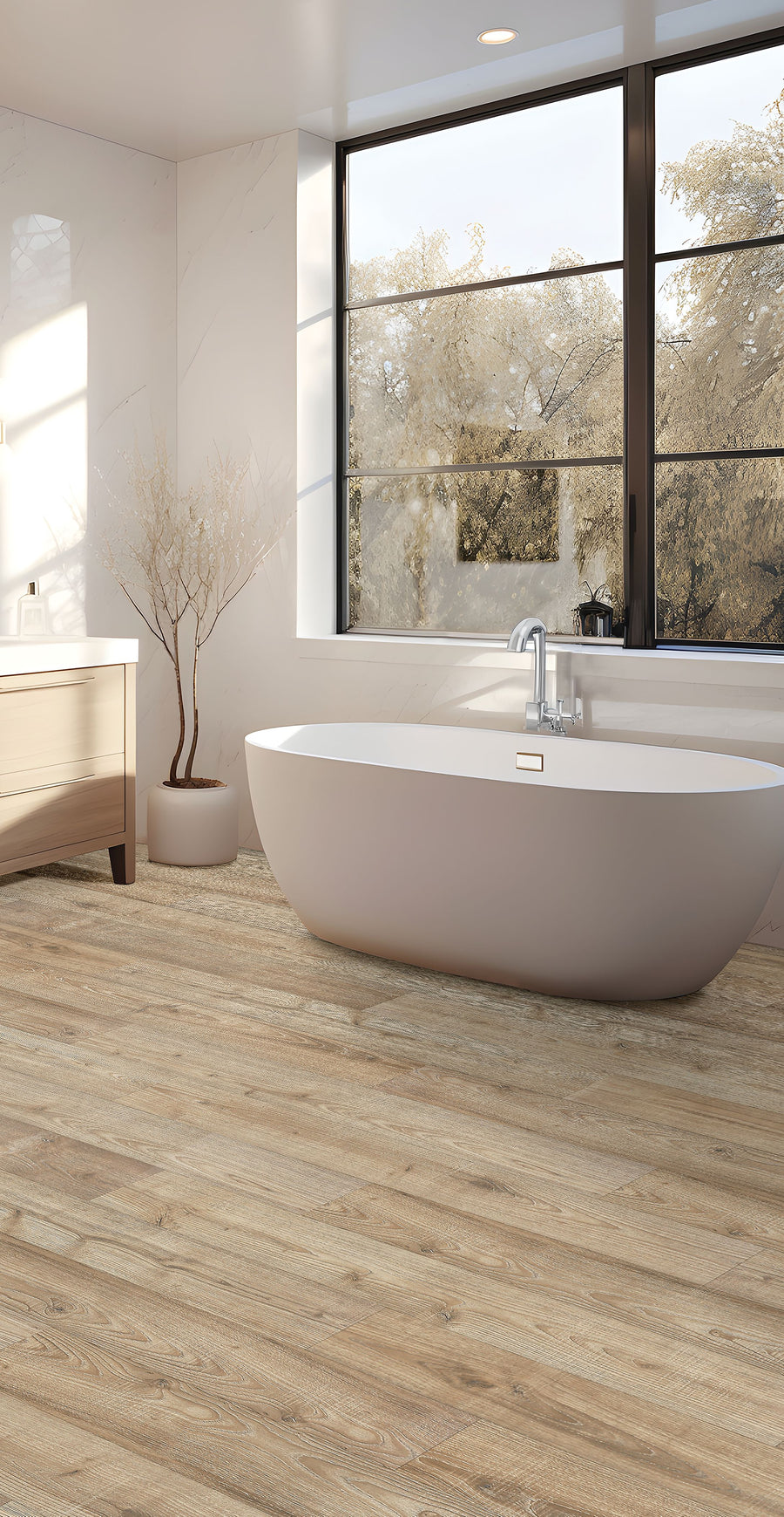 A modern bathroom with a freestanding oval bathtub, large windows showing trees outside, light wood flooring, a white vanity with drawers, and a minimalist potted tree in the corner.