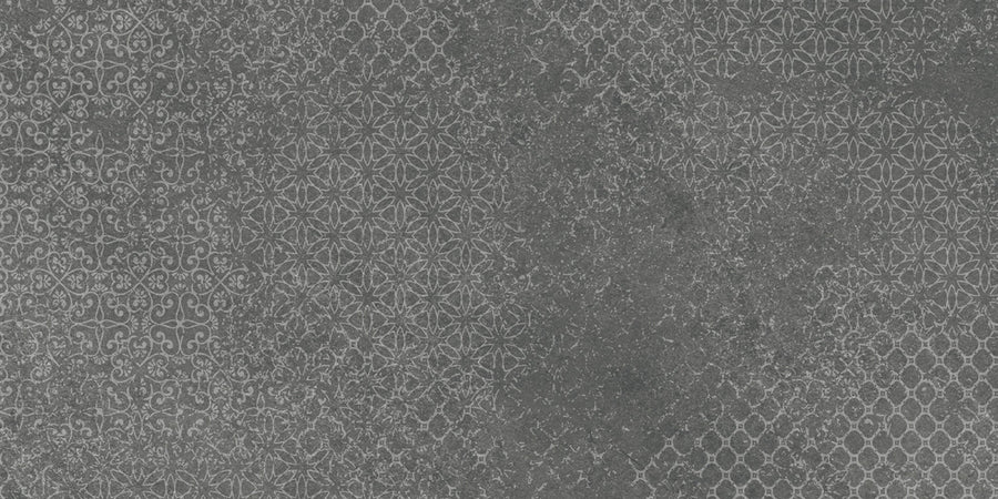 A dark gray, textured surface with faded geometric and floral patterns reminiscent of vintage style, similar to Shyft 24x48 Lace Deco tile. The subtle, partially worn designs create an aged, distressed appearance.