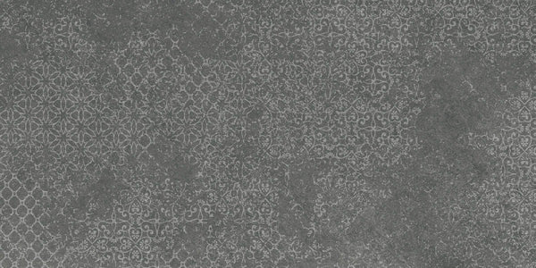 The Shyft 12x24 Lace Deco features a textured dark gray surface inspired by Brazilian slate, with repeating white lace-like patterns for a decorative, slightly distressed vintage tile look.