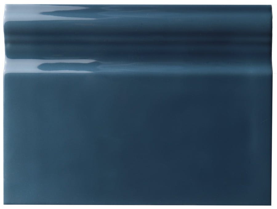 The Zephyr 6x8 Ceramic Baseboard, a glossy blue rectangular tile with a slightly raised top edge inspired by Mediterranean baseboard styles, is showcased against a plain white background.
