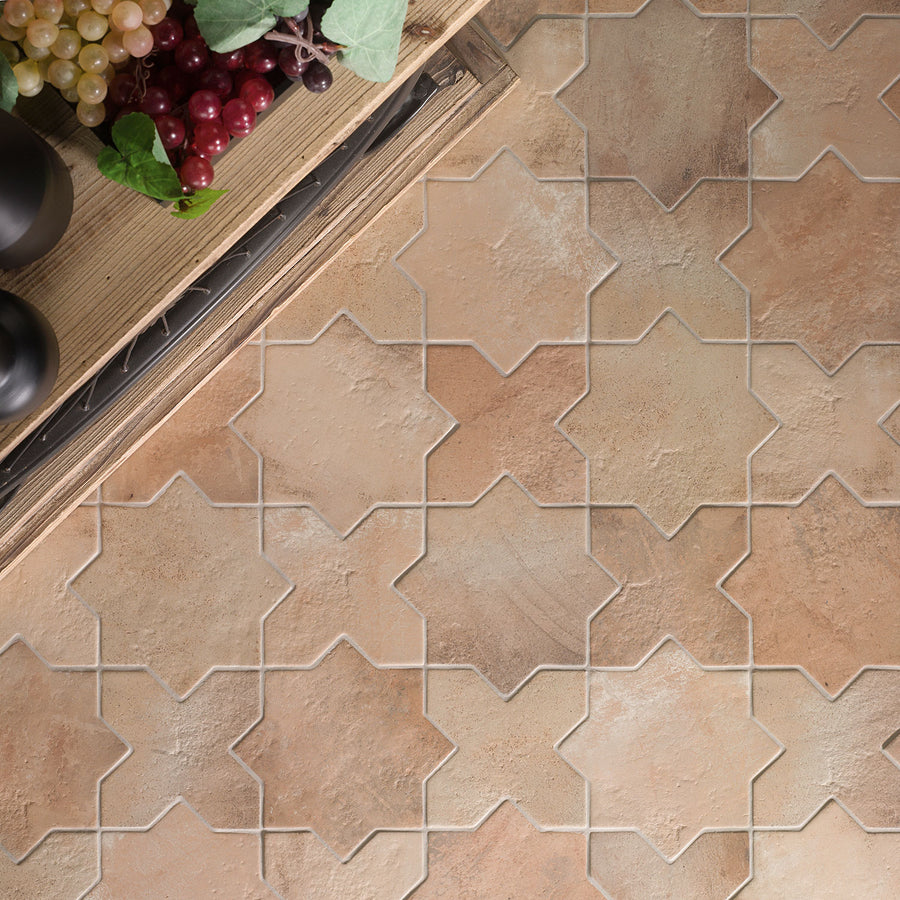 A kitchen countertop with grapes and vegetables is next to a floor with tan and beige star-shaped tiles arranged in an interlocking geometric pattern.