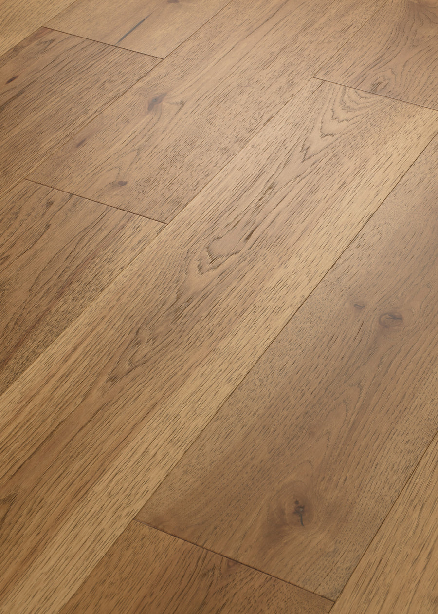 Close-up of Birmingham Pecan 7 1/2" Hardwood flooring, showcasing light brown boards with distinct wood grain and natural knots in a staggered pattern. The surface looks smooth and expertly finished.
