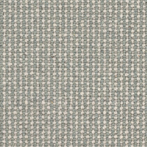 Close-up of Andros Berber Carpet in Sage shows a woven pattern with vertical rows of small, raised white dots on a light gray-green background, offering an evenly textured surface that looks both soft and durable.