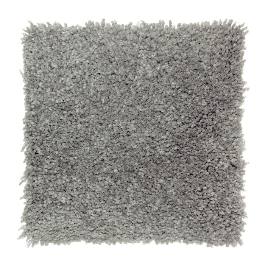 A square swatch of Sensible Style III Family Friendly Carpet in Egyptian Jewel, featuring light gray plush, shaggy pile and slightly uneven edges for a soft, thick texture that adds comfort and modern style to any room.