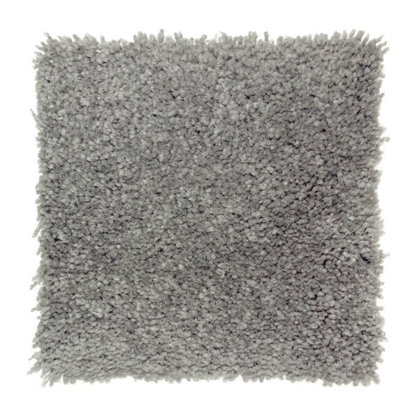 A square swatch of Sensible Style III Family Friendly Carpet in Egyptian Jewel, featuring light gray plush, shaggy pile and slightly uneven edges for a soft, thick texture that adds comfort and modern style to any room.