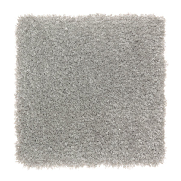 A square sample of Sensible Style III Family Friendly Carpet in Aspen Summitt—a light gray, plush, and dense textured carpet. Its slightly uneven edges highlight fluffy fibers, adding comfort and style to any modern space.