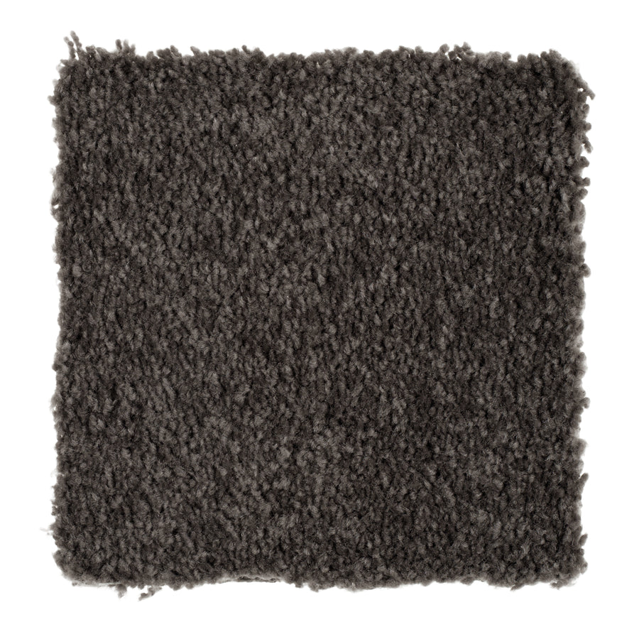 A close-up of Sensible Style III Family Friendly Carpet in Meteorite shows its dark gray, textured, plush surface—perfect for adding everyday comfort to any room.