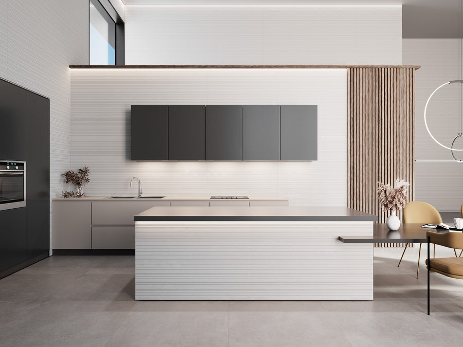 Minimalist modern kitchen with sleek gray cabinets, a large central island, built-in oven, and subtle lighting. Pale floors and vertical wood slats add texture, while dried plants in vases provide decorative accents.