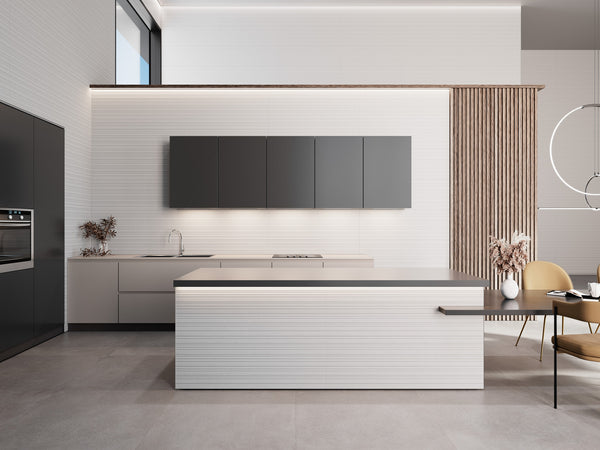 Minimalist modern kitchen with sleek gray cabinets, a large central island, built-in oven, and subtle lighting. Pale floors and vertical wood slats add texture, while dried plants in vases provide decorative accents.