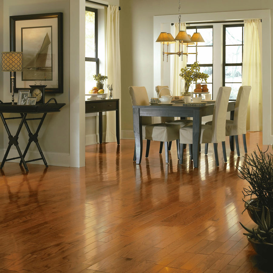 A bright dining room with wooden floors, a rectangular dining table with six white chairs, large windows with white curtains, and a console table with a lamp and framed artwork.
