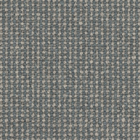 Close-up of Andros Berber Carpet in Shoreline color, highlighting the blue and off-white woven pattern. The tightly interlaced fibers form a grid-like texture, showcasing the durability and detail typical of premium Berber carpet designs.