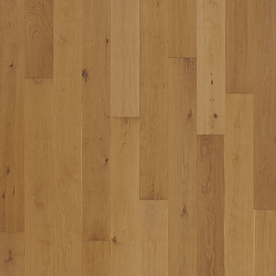 Close-up of Barton Hall 7 1/2" European White Oak Hardwood flooring, highlighting natural grain patterns and warm light brown tones. Staggered planks showcase subtle variations, enhancing the luxury appeal.
