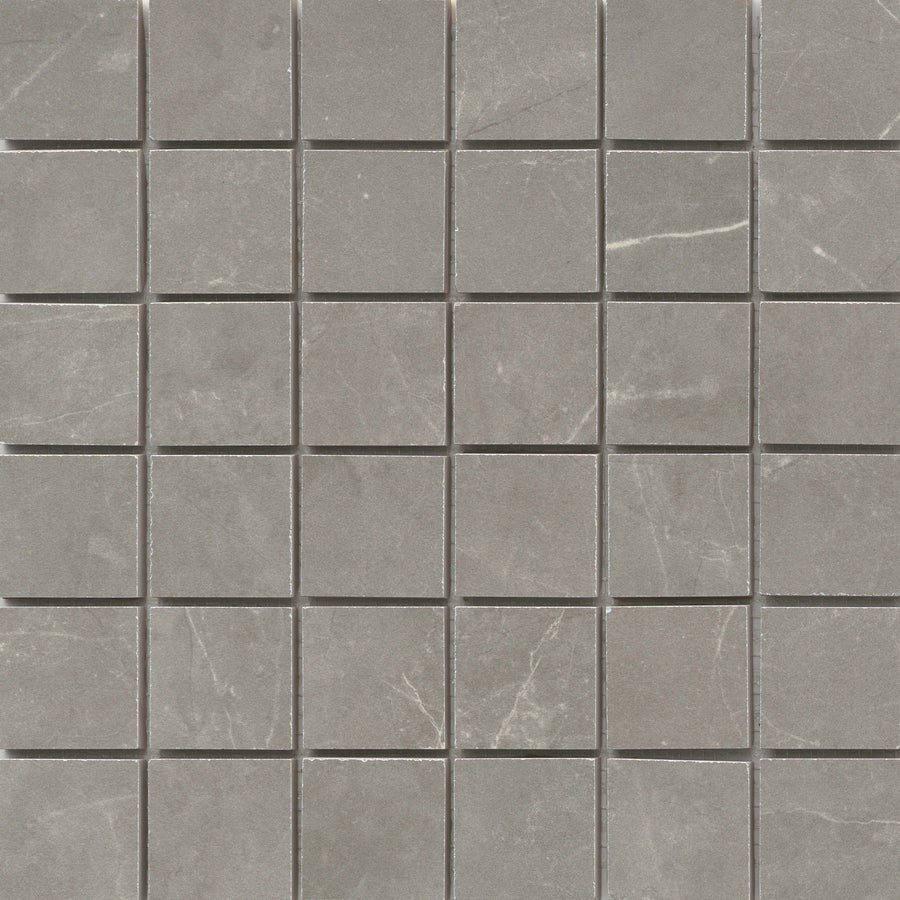 The Callie 2x2 Porcelain Mosaic in Fog features small, square tiles with subtle white veining and a matte finish, creating a refined checkerboard pattern with slight variations in texture and color.