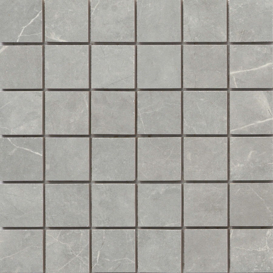 The Callie 2x2 Porcelain Mosaic in Moonlight features square tiles arranged in a precise grid, showcasing a gray marble look with delicate white veining for an elegant, evenly spaced pattern.