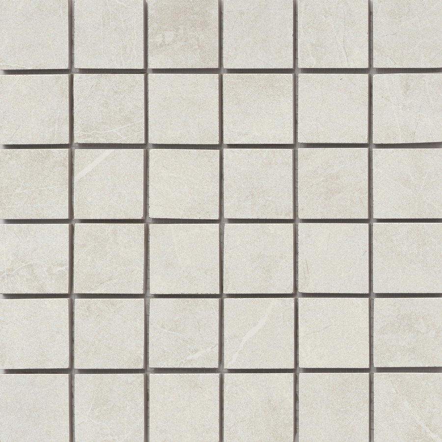 The Callie 2x2 Porcelain Mosaic in Steel features square, light gray tiles with subtle white veining and a smooth, matte finish. They are evenly aligned in a grid pattern and separated by thin dark grout lines.