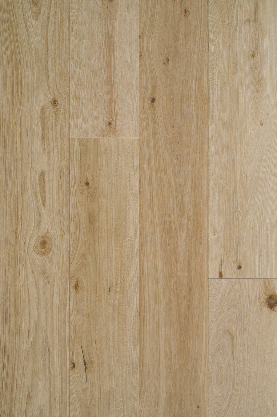 The Tribeca Loft French Oak 9.4" Hardwood in Sunset Park features wide-plank boards with visible grain and natural knots. Smooth surfaces display pale beige to warm honey hues, enhancing the wood’s organic character.