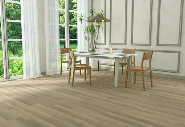 A bright dining room with large windows, a white table set for four with wooden chairs, a gold pendant light, light wood flooring, and green plants. Sunlight streams in, highlighting the modern, airy decor.