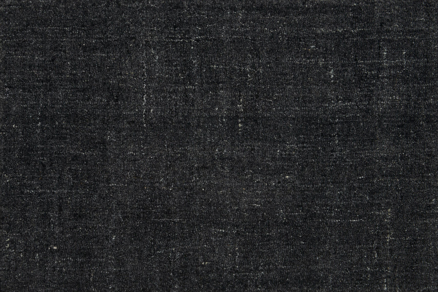 Close-up of Terrain On Trend Carpet in Mineral—a textured, dark gray woven surface with lighter streaks and a hint of vintage charm, ideal for contemporary commercial spaces. Visible threads enhance its soft appeal.