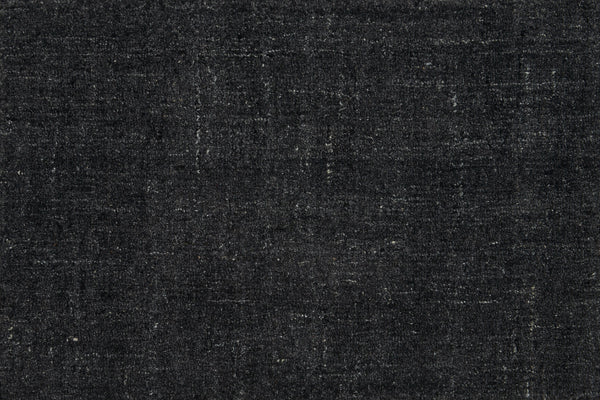Close-up of Terrain On Trend Carpet in Mineral—a textured, dark gray woven surface with lighter streaks and a hint of vintage charm, ideal for contemporary commercial spaces. Visible threads enhance its soft appeal.