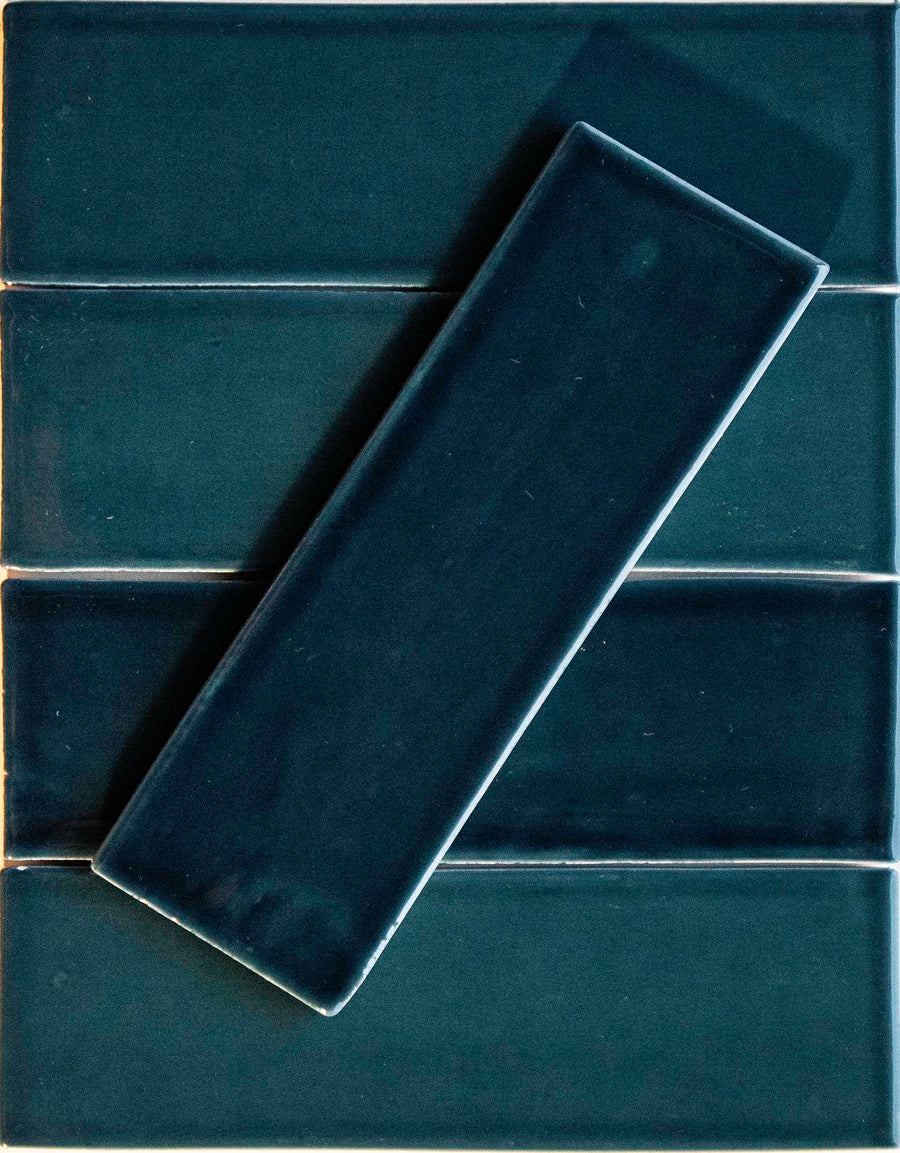 Four Teal Me More Noir Crackle 2.5x8 ceramic tiles are arranged horizontally, with one matching hand-dipped tile placed diagonally on top.