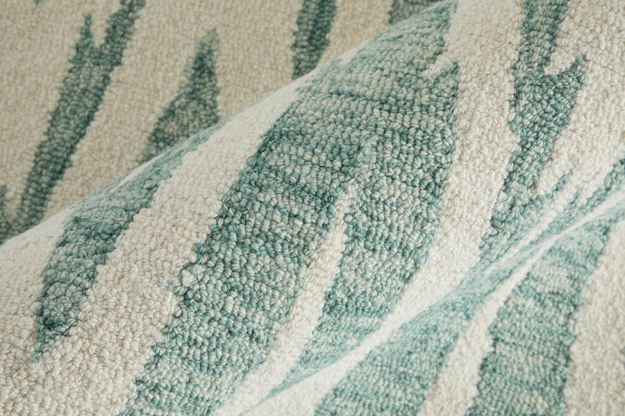 Close-up of a textured woven fabric with a cream and light teal zigzag or abstract pattern, showing raised, looped threads and intricate detail.