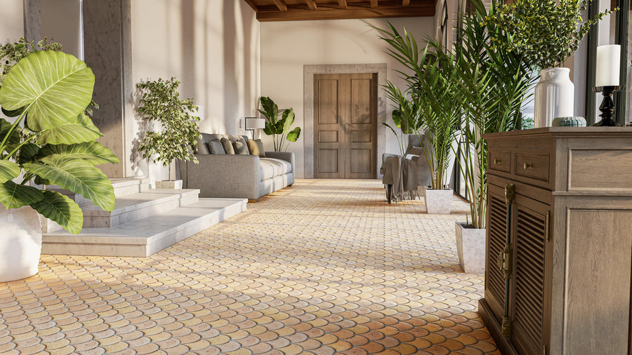 A sunlit hallway with patterned tile flooring, lush green potted plants, a wooden sideboard, and a seating area featuring a gray sofa and armchairs near steps leading to a doorway.