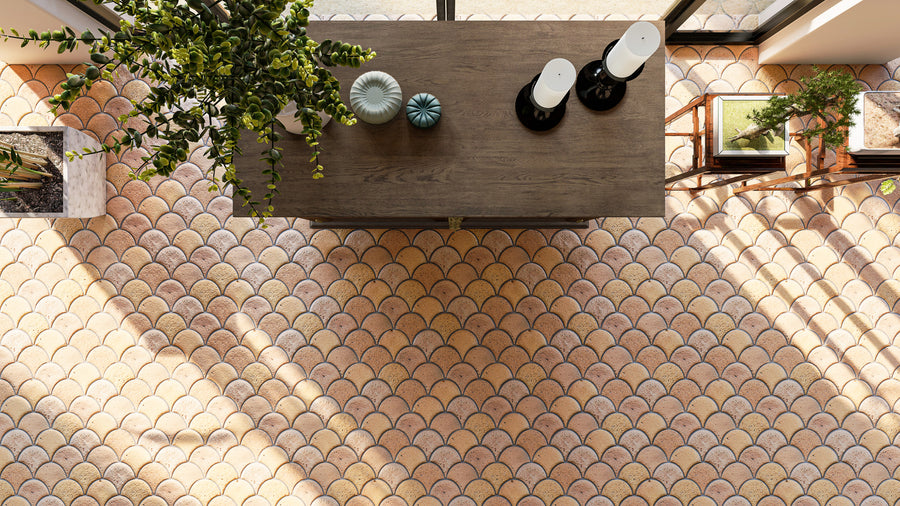 Overhead view of a wooden table with decorative vases and candles, surrounded by plants. The floor features a fish scale pattern of light brown and pinkish tiles, with sunlight casting shadows across the scene.