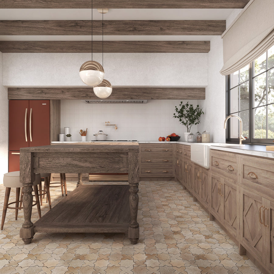 Rustic kitchen with wooden cabinets, exposed ceiling beams, a large wooden island with stools, tile flooring, a farmhouse sink, a red refrigerator, and a window letting in natural light.