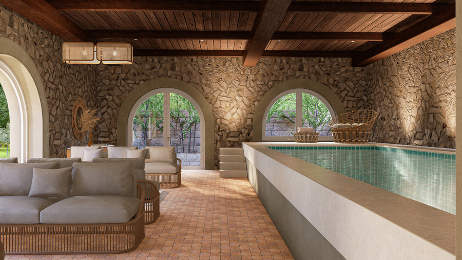 A luxurious indoor pool room with stone walls, arched windows, wooden ceiling beams, and modern rattan furniture. Sunlight streams through the windows, illuminating the elegant and cozy seating area beside the pool.