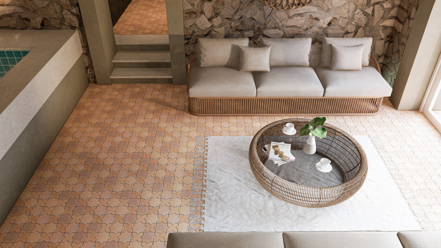 A cozy living area with a wicker sofa, neutral cushions, a round wicker coffee table on a white rug, and stone accent wall. Sunlight pours in through a nearby window, creating a warm, inviting atmosphere.