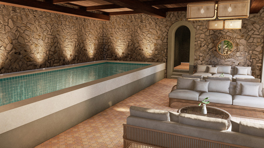 A luxurious indoor pool room with stone walls, a rectangular tiled pool, cushioned lounge sofas, a round glass coffee table, soft lighting, and a large arched doorway leading to another space.
