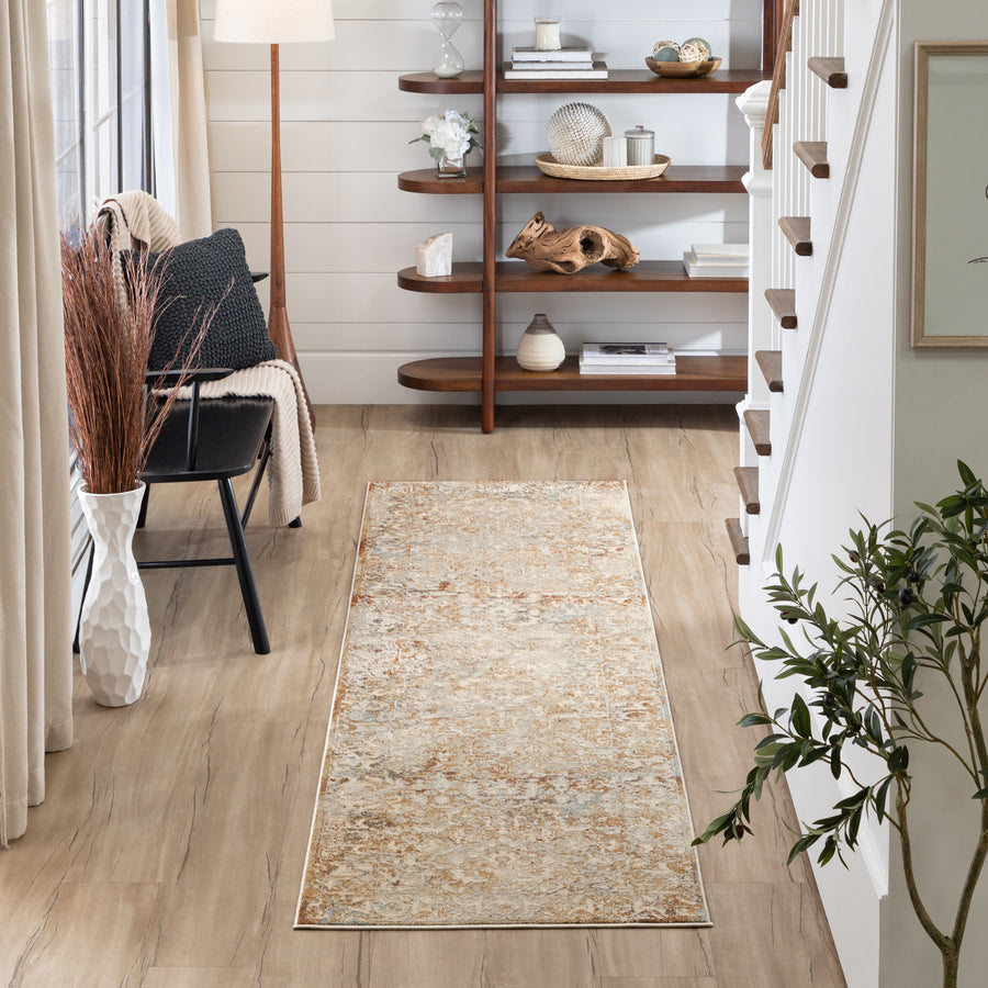 A cozy hallway with light wood flooring, a beige patterned runner rug, a black chair with a pillow and blanket, a white vase with tall branches, a floor lamp, a plant, and a wall-mounted wooden shelf with decor.