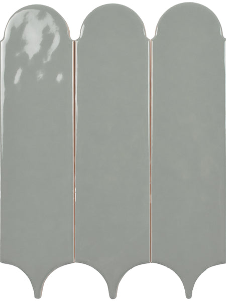 Three vertical Tranquill 3x12 Glazed Ceramic Tiles in glossy light gray, with rounded tops and pointed bottoms, are arranged side by side in a repeating scalloped pattern for a timeless neutral look.