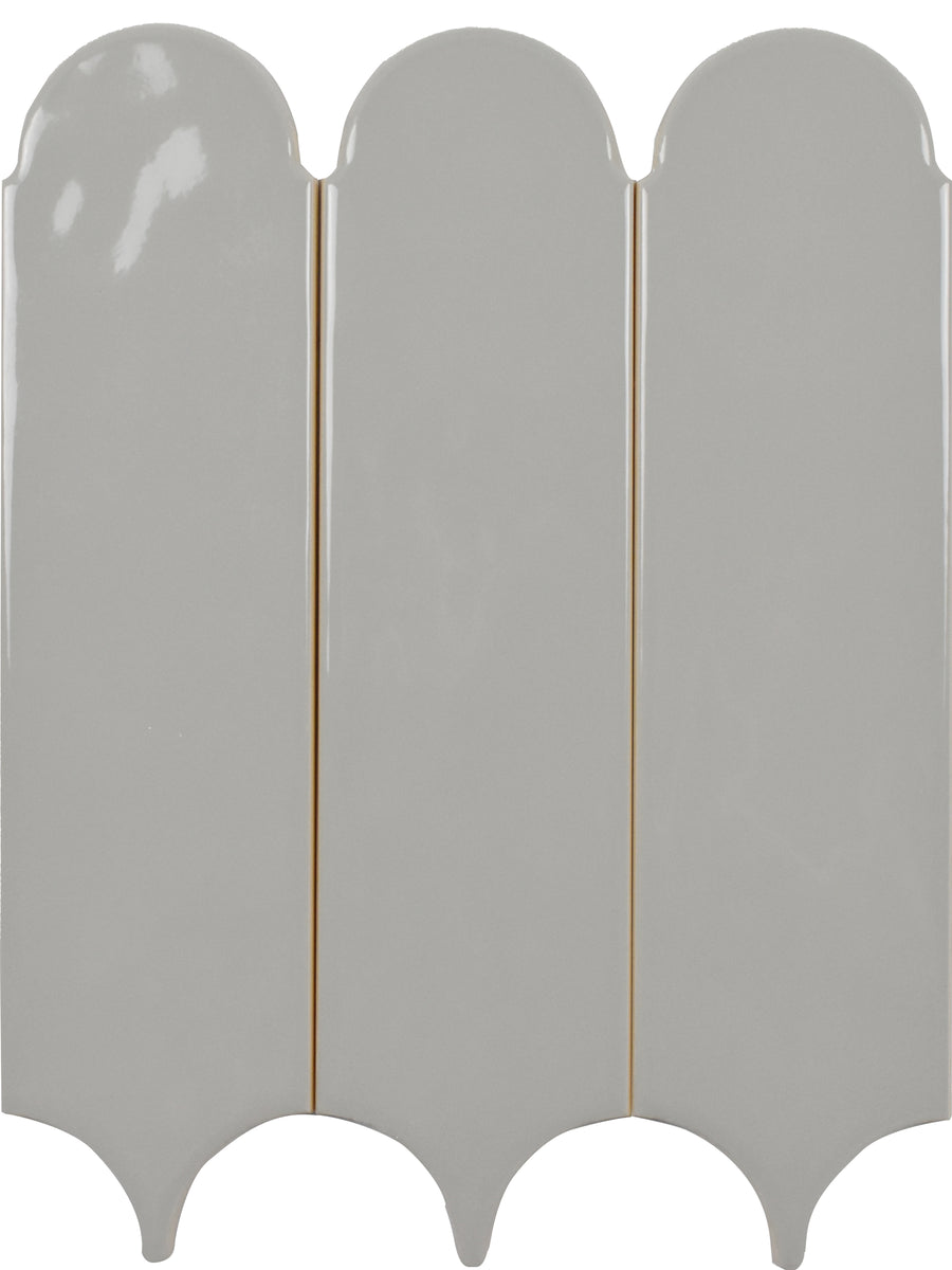 The Tranquill 3x12 Glazed Ceramic Tile features a light gray finish with three vertical, rounded arches at the top and curved cutouts at the bottom, separated by narrow grooves for a timeless look.