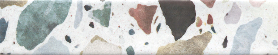 The Fragmento 2x10 Ceramic Tile in Tutti Frutti features a terrazzo-look with bold, irregular stone fragments in green, brown, gold, gray, pink, and black embedded on a white background.