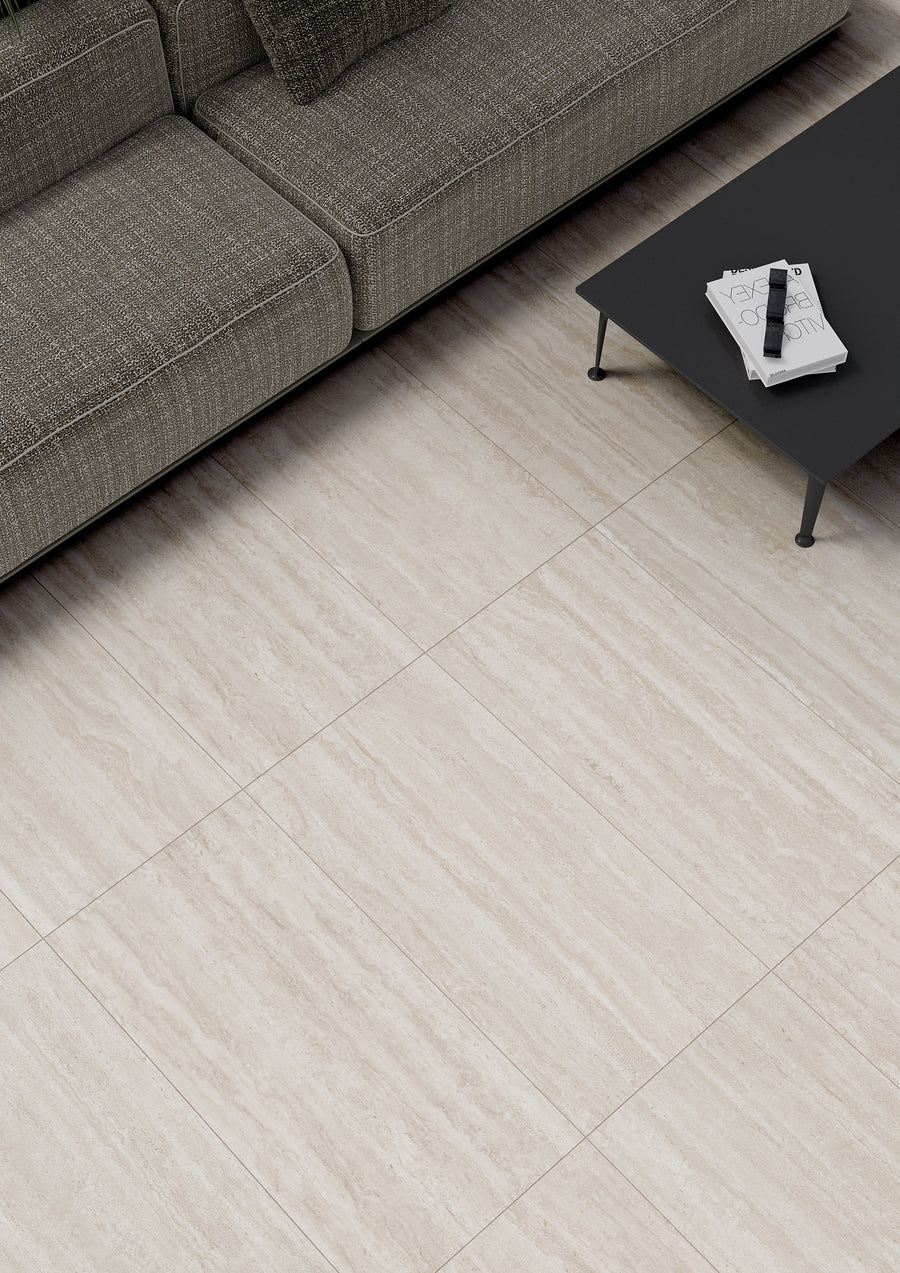 A modern living room with beige, stone-like tile flooring, a gray fabric sofa with cushions, and a black coffee table holding a magazine and a remote control.