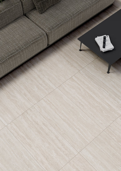A modern living room with beige, stone-like tile flooring, a gray fabric sofa with cushions, and a black coffee table holding a magazine and a remote control.