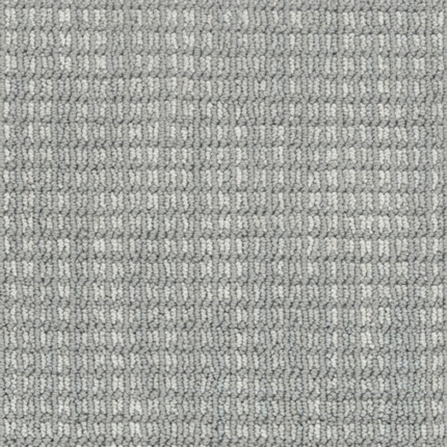 Close-up of Haven Berber Carpet in Upward color, featuring tightly woven fibers and a textured, grid-like pattern that creates a subtle checkered design with varying shades of gray.