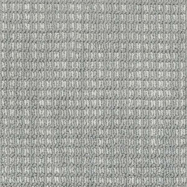 Close-up of Haven Berber Carpet in Upward color, featuring tightly woven fibers and a textured, grid-like pattern that creates a subtle checkered design with varying shades of gray.
