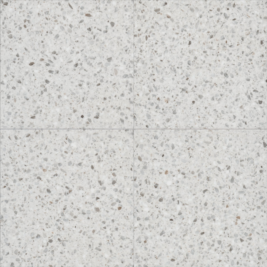 Coretec Solid Polymer Core Vinyl Tile features four square terrazzo tiles with a light gray base and scattered gray, white, and beige stone fragments, creating a subtle pattern at intersections—perfect for stylish, durable luxury flooring.