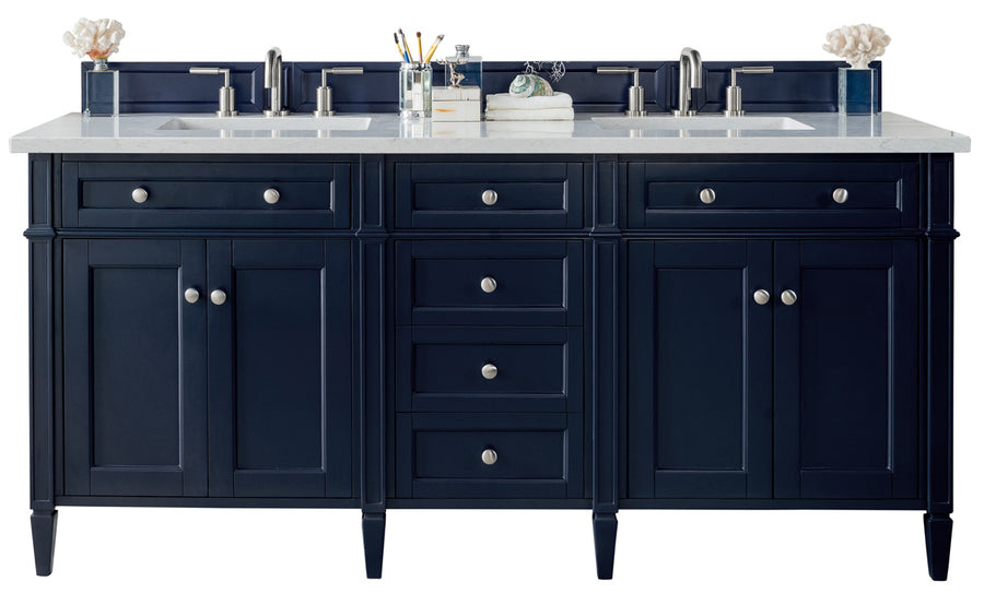 A navy blue double-sink bathroom vanity with silver hardware, a white countertop, dual faucets, organized toiletries, and decorative coral accents on each corner.