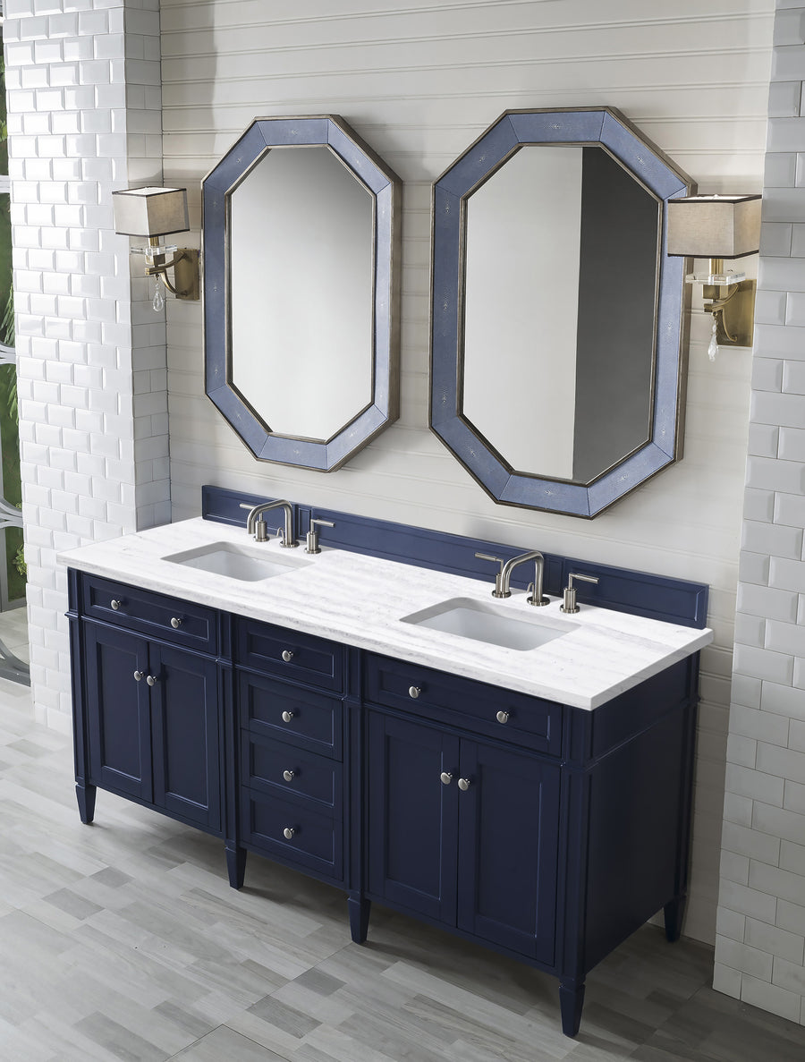 A modern bathroom with a navy double-sink vanity, white countertop, two octagonal mirrors above, and twin wall sconces. The walls are covered in white tile, and the floor has light gray tiles.