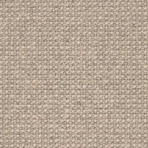 Close-up of Andros Berber Carpet in Village color, featuring a tightly woven, looped pattern. The durable carpet shows a soft, uniform surface with subtle beige shade variations throughout its textured weave.