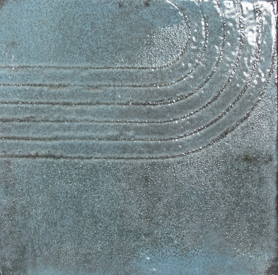 The Wabi 5" x 5" Ceramic Tile in blue features a glossy, textured surface with four curved raised lines in the upper right, offering a modern abstract look and unique handcrafted variations.